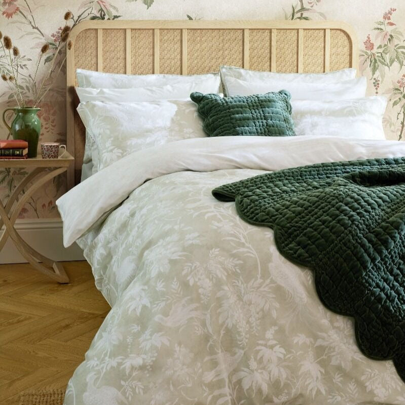 Bedroom with floral wallpaper, wicker headboard, and white bedding with green accents.