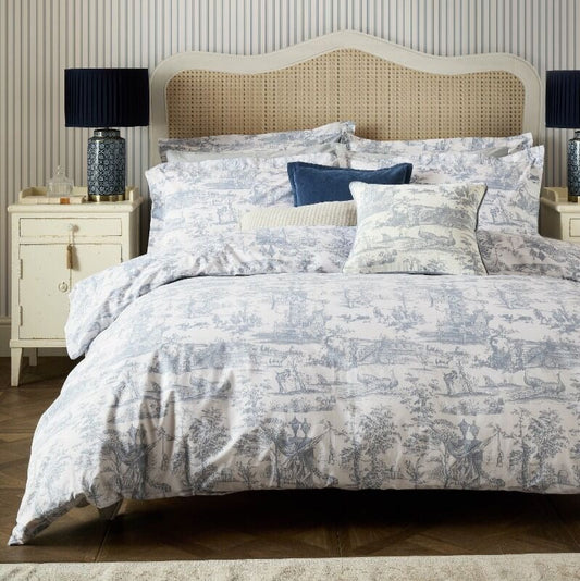 Bedroom with blue floral bedding, pillows, and lamps against a striped wall.