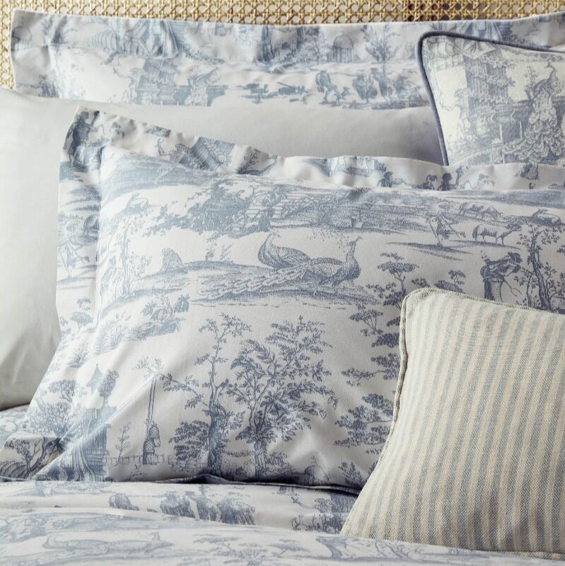 Decorative pillows with blue and white pattern on a bed with a textured headboard.