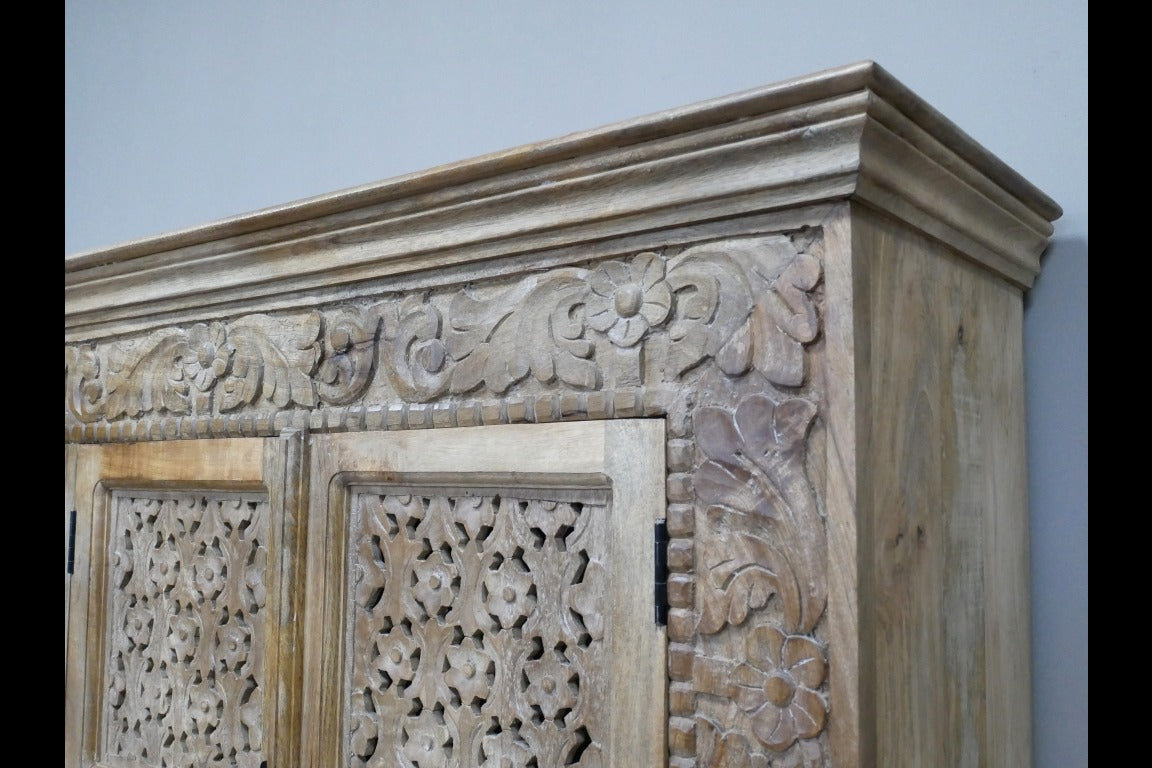 A large, hand-carved solid wood sideboard measuring 190cm wide by 101cm high, featuring four intricately detailed doors with metal handles. The natural rustic finish highlights the ornate floral and geometric carvings, adding a touch of artisanal craftsmanship. Behind the doors are two spacious cupboards with internal shelves, offering ample storage. The wide counter-top provides additional surface space, making this piece both functional and decorative for various interior settings.
