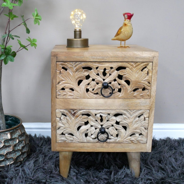Compact bedside cabinet measuring 48cm in height, 36cm in width, and 37cm in depth, crafted from solid mango wood. Features two drawers with intricately hand-carved floral and geometric patterns on the fronts, finished in a natural wood tone. The cabinet's rustic design and rustic charm make it suitable for various interior styles, including bohemian, farmhouse, and eclectic decors.