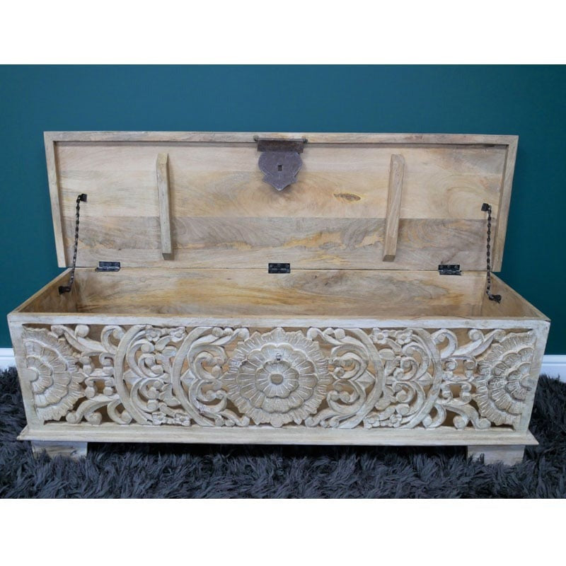 A handcrafted storage bench made from solid mango wood, measuring 135cm wide, 40cm deep, and 46cm high. The bench features a whitewashed finish and intricately carved floral and geometric patterns on its front panel. It includes a lift-up lid revealing a spacious internal compartment, offering both seating and storage solutions. The rustic design and boho craftsmanship make it suitable for various interior styles, including bohemian, farmhouse, and eclectic decors.
