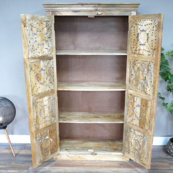 A tall, hand-carved solid mango wood cabinet measuring 180cm in height, 99cm in width, and 41cm in depth. The cabinet features two full-length doors adorned with intricate floral and geometric carvings, reflecting Eastern design influences. Finished in a natural wood tone, this piece offers ample internal storage with shelved compartments, making it both functional and decorative.
Suitable for various interior styles, including bohemian, rustic, and eclectic decors.