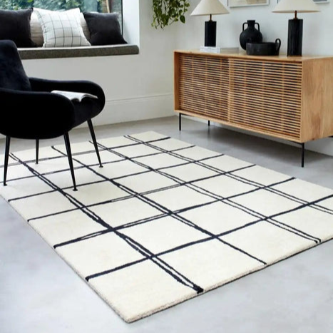 Modern living room with a checkered rug, wooden sideboard, and black armchair.