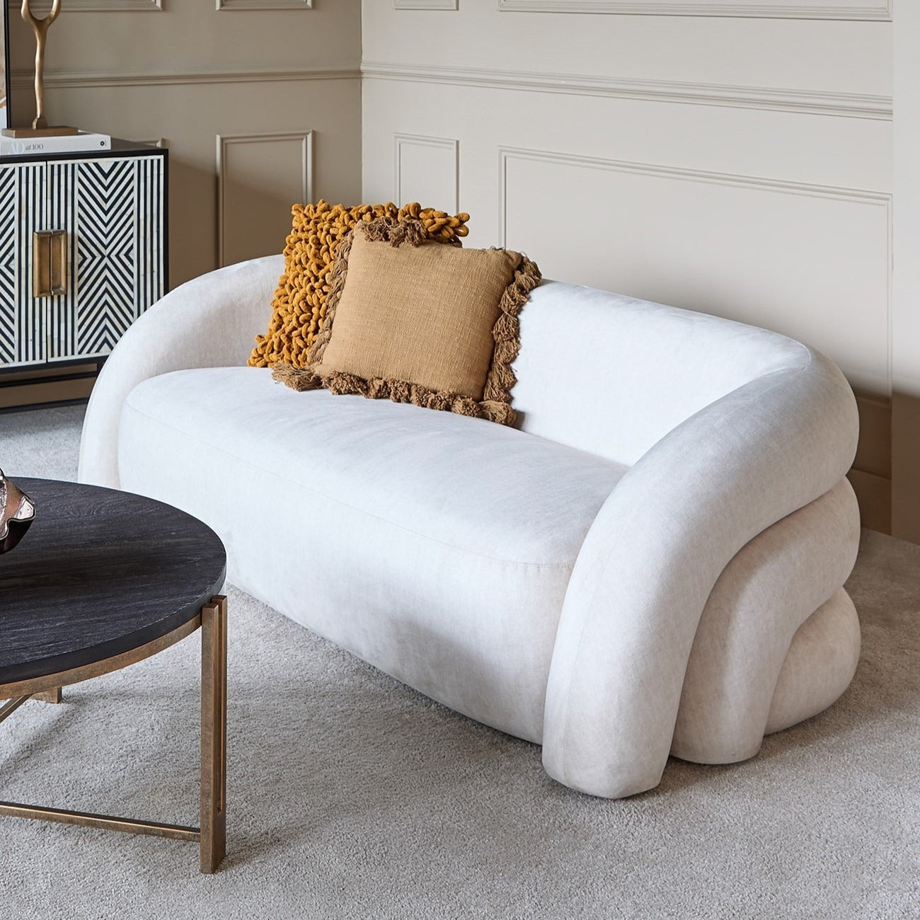 White curved sofa with decorative pillows in a modern living room setting.