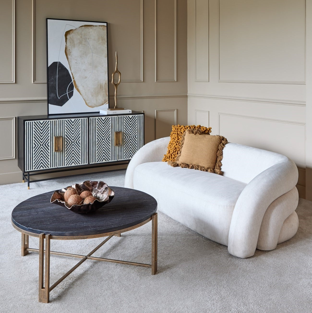 Modern living room with a white sofa, round coffee table, and decorative wall art.