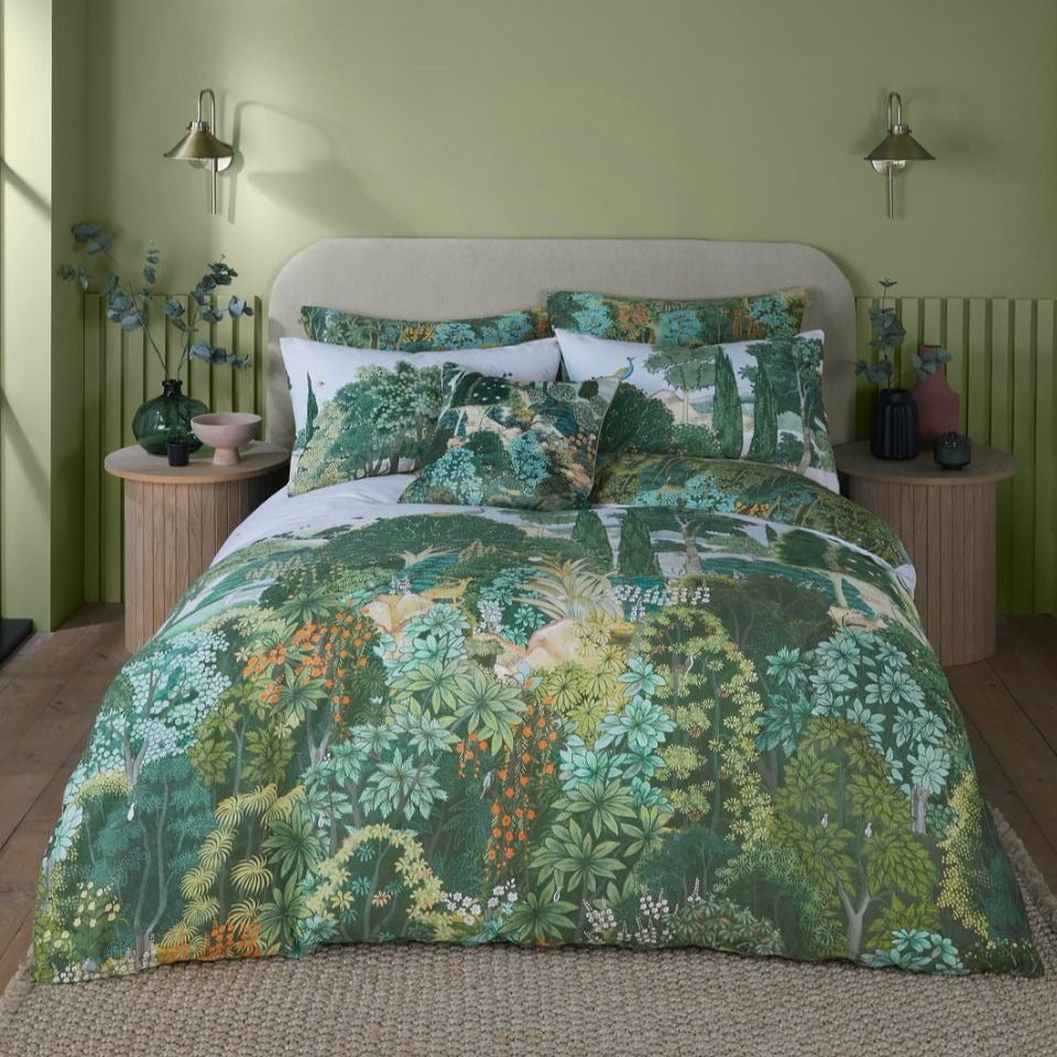 A bed with green, orange, and yellow floral bedding in a room with green walls and wooden flooring.