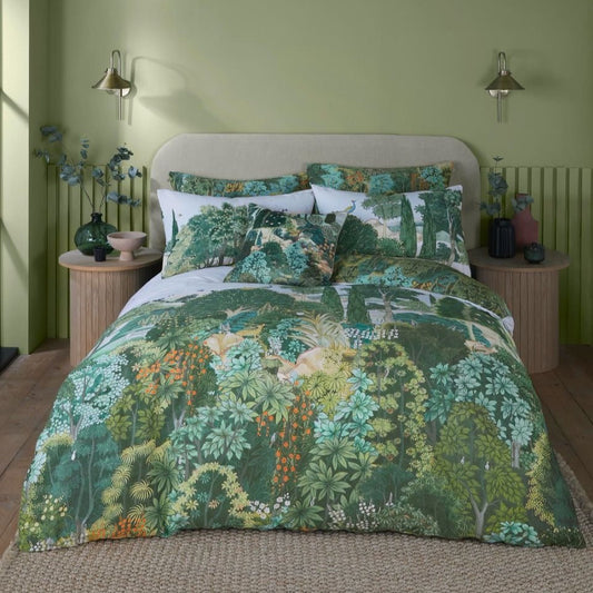 A bed with green, orange, and yellow floral bedding in a room with green walls and wooden flooring.