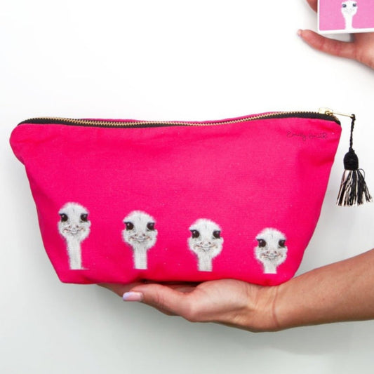 Hot pink makeup bag with ostrich illustrations held by a hand.