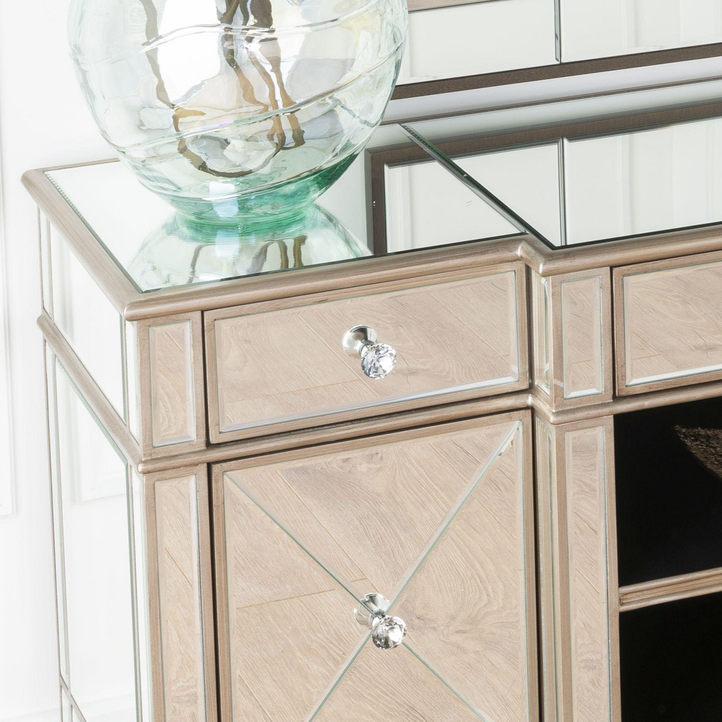 Beige mirrored console table with glass top and decorative items.