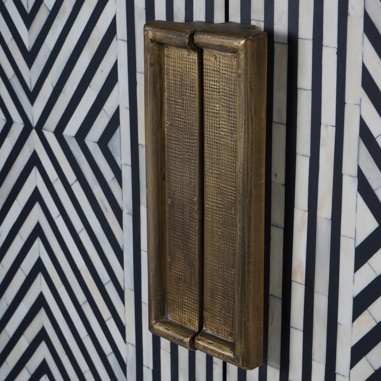 Bronze door handle on a cabinet with black and white pattern
