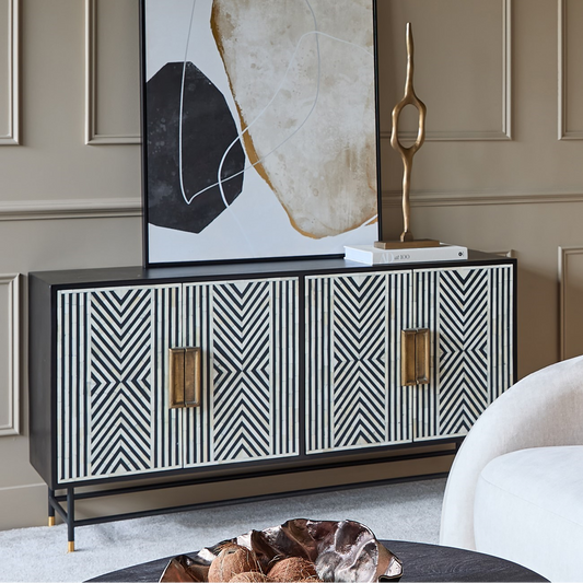 Modern interior with a black and white patterned cabinet, abstract art, and decorative sculpture.