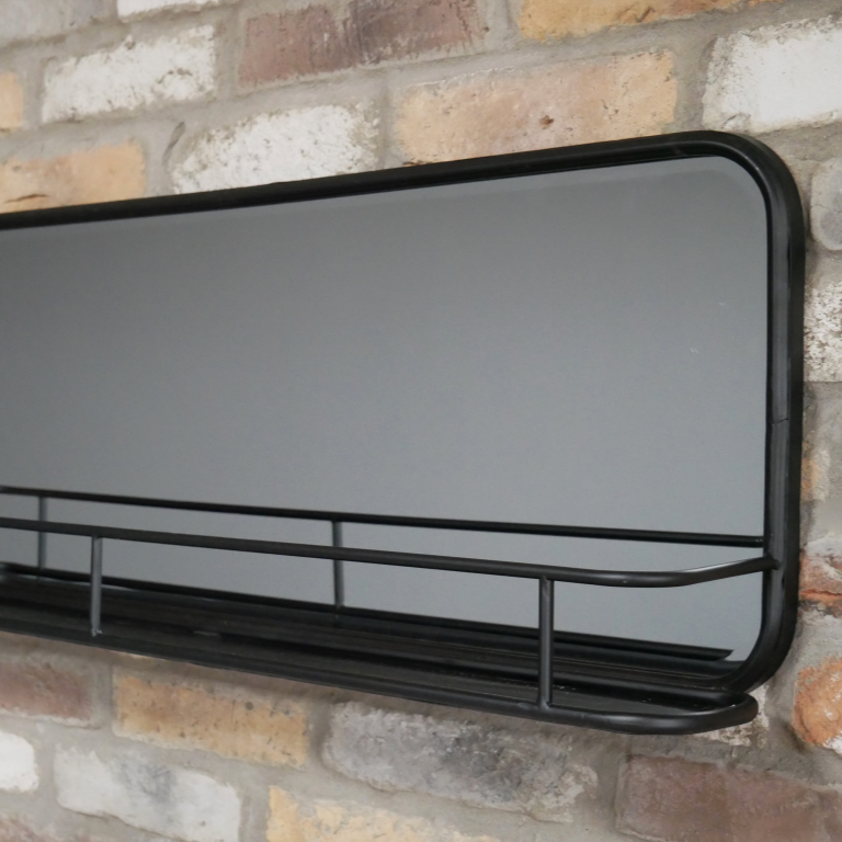 Black-framed mirror with shelf on a brick wall