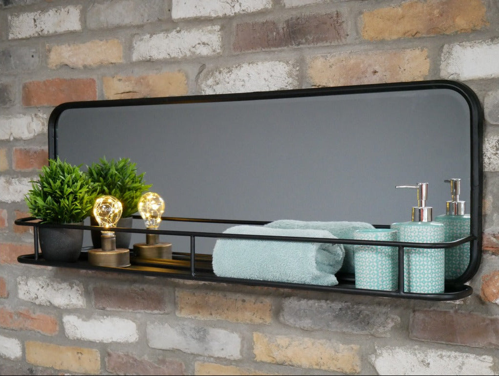 Transform your wall with the Industrial Wall Mirror With Shelf. The unique rectangular shape creates a welcoming focal point while the sturdy black metal frame adds a touch of modern industrial charm to your home. Includes a convenient built-in shelf so you can easily display your cherished items! This versatile mirror fits effortlessly into modern homes, and it even works in more rustic environments. Combine style with function!