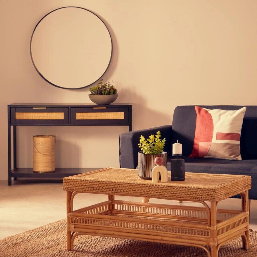 Living room with a wicker coffee table, blue sofa, and decorative items.