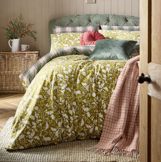 Bedroom with green floral duvet and plaid blanket on a bed with wooden headboard