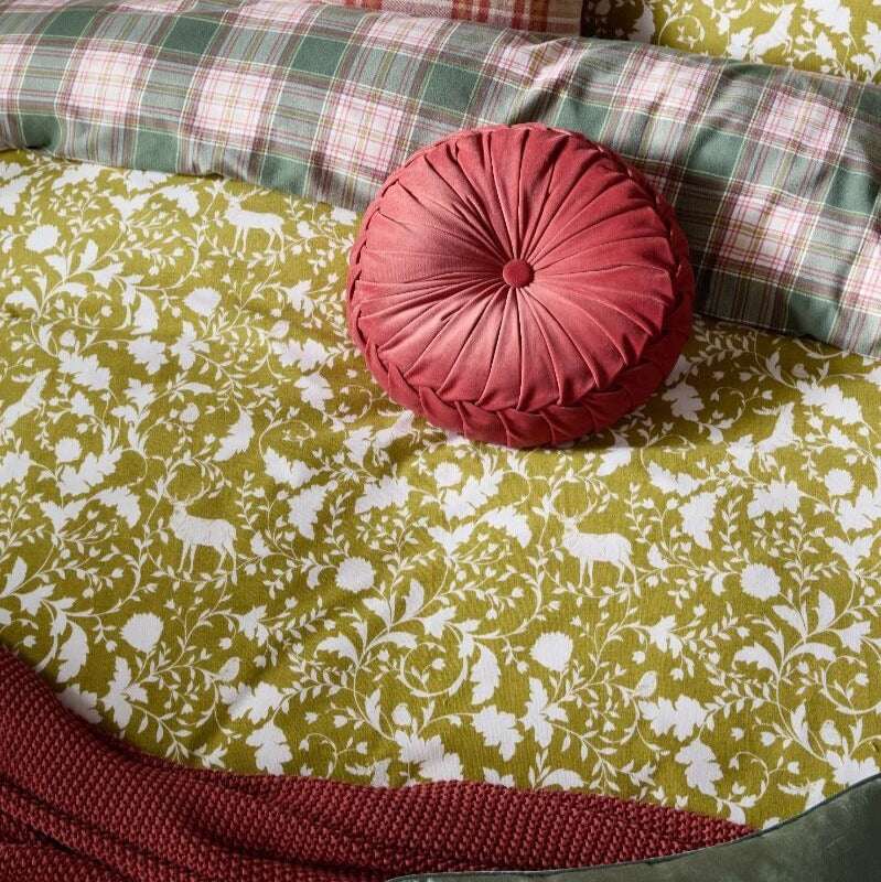 Olive green patterned duvet with a pink round pillow on a sofa