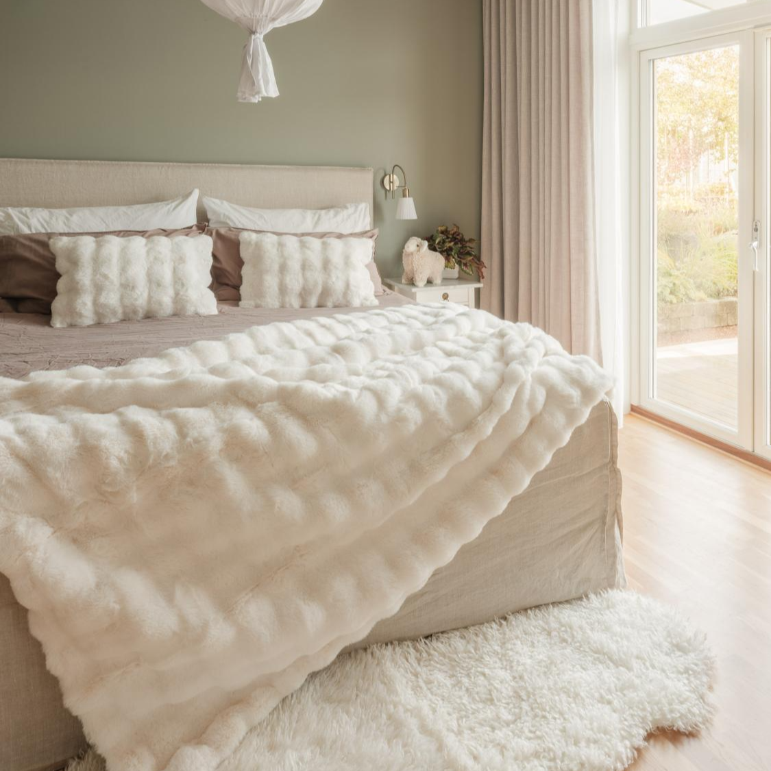 Neatly made bed with white comforter in a bright bedroom