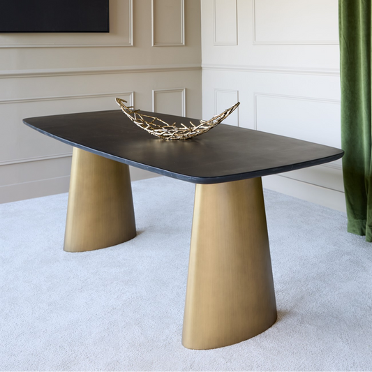 Modern coffee table with gold legs and a black top in a room with white walls and a green curtain.