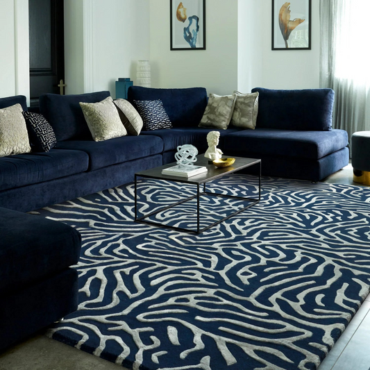 Modern living room with a navy sectional sofa and patterned rug.