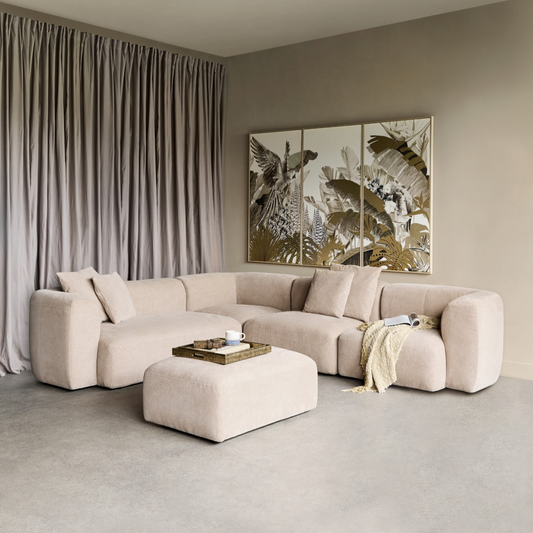 Modern living room with a beige sectional sofa, ottoman, and abstract artwork on the wall.
