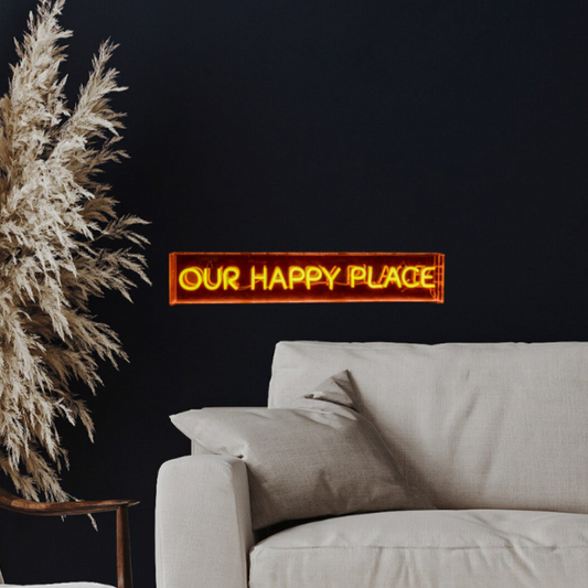 Neon sign reading 'OUR HAPPY PLACE' above a sofa with decorative elements.