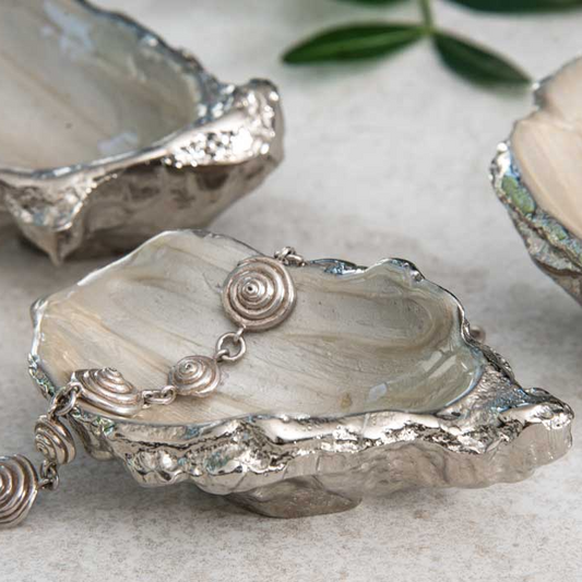 Decorative silver oyster shells with intricate designs on a light background