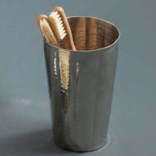 Metal cup with wooden toothbrushes on a gray background