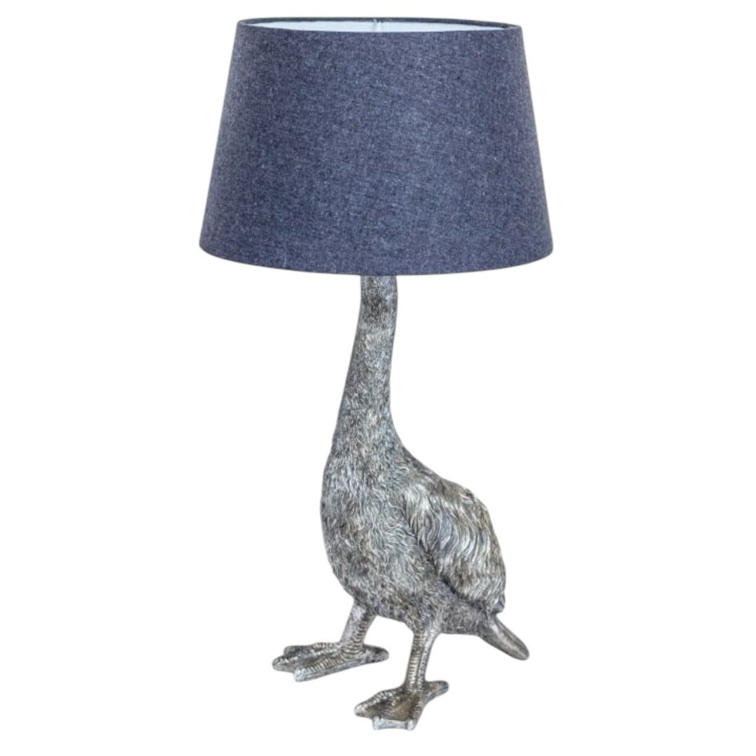 A quirky silver table lamp in the shape of a goose, with a dark blue lampshade.