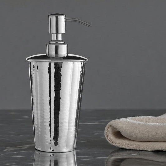 Silver soap dispenser on a dark surface with a beige towel in the background