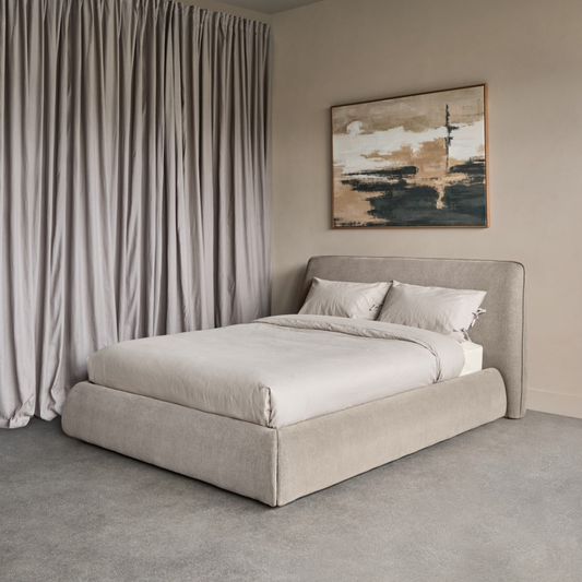 Modern bedroom with a beige bed, abstract painting, and draped curtains.