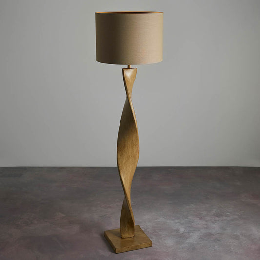 Wooden floor lamp with a beige shade on a gray floor and background