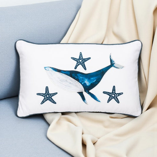 Decorative pillow with whale and starfish design on a light blue couch.