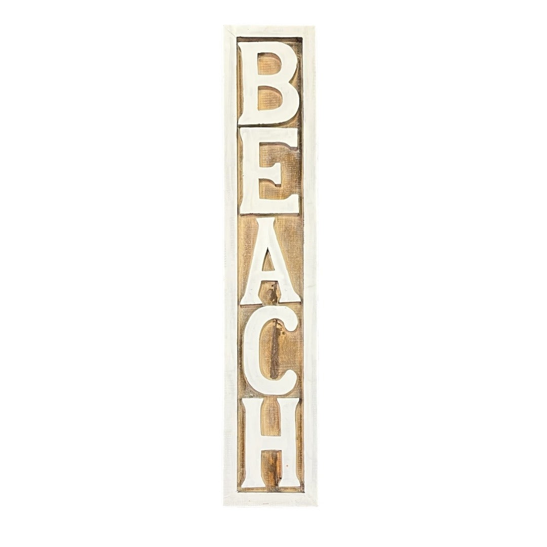 A wooden sign, vertically oriented reading "beach", with a natural wood surface and the text in white capital letters. Coastal decor style.