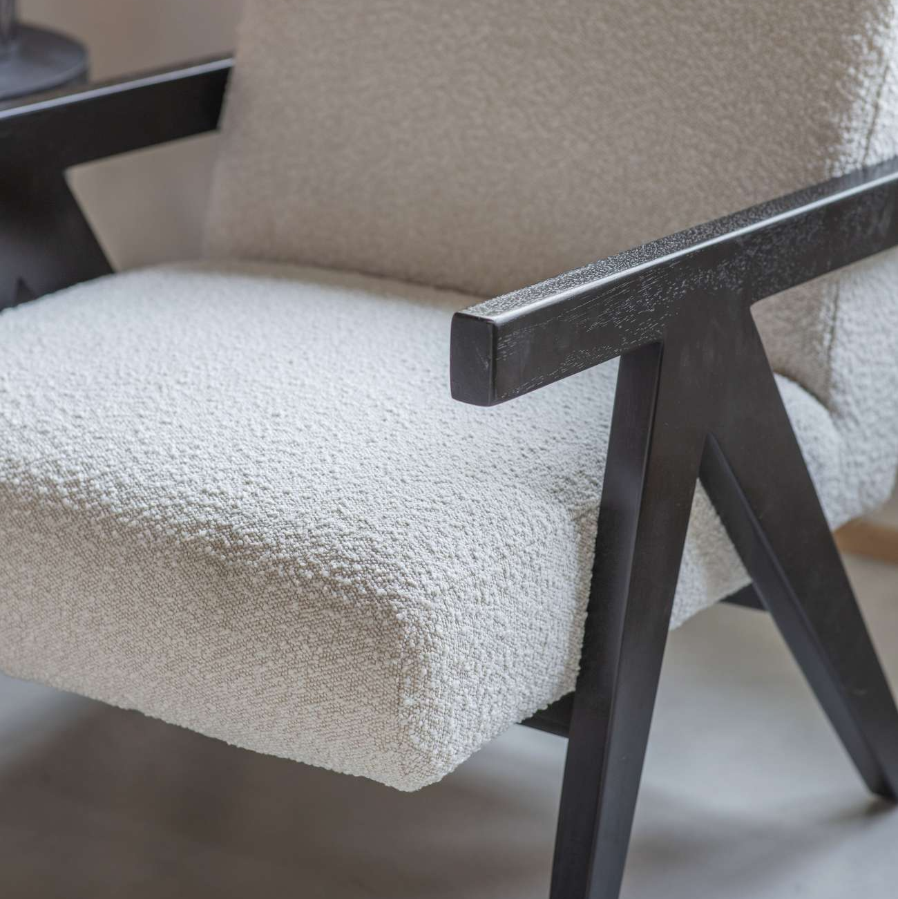 Close-up of a chair with cream cushioned seat and backrest, black metal frame.