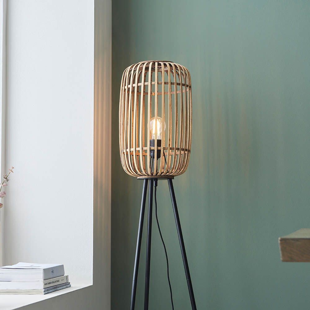 Wooden floor lamp with a light bulb on a green wall background