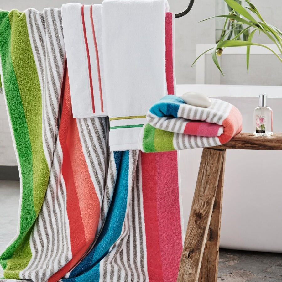 Colorful striped towels draped over a wooden stool in a bright room.