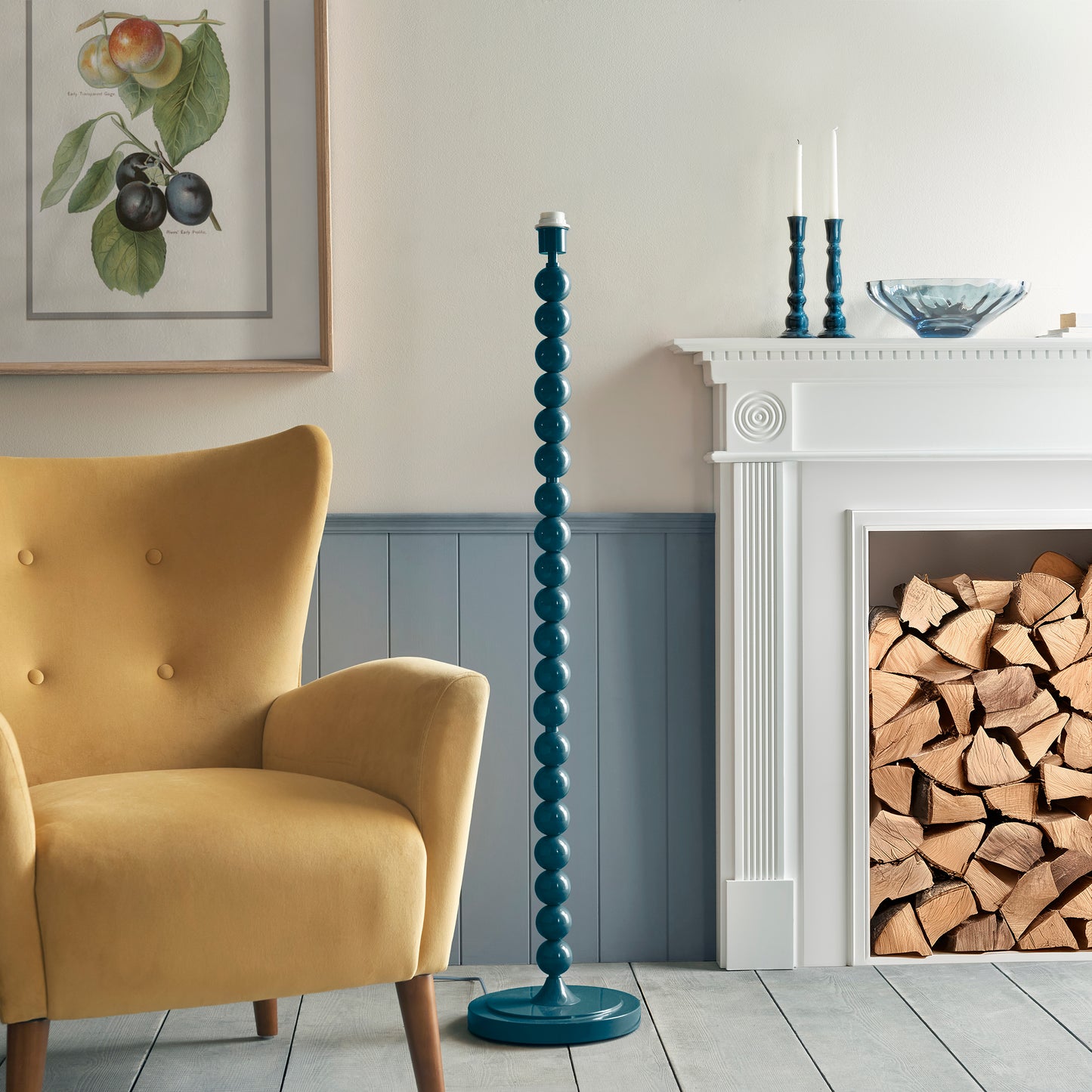 Living room with yellow armchair, blue floor lamp, and fireplace with wood.