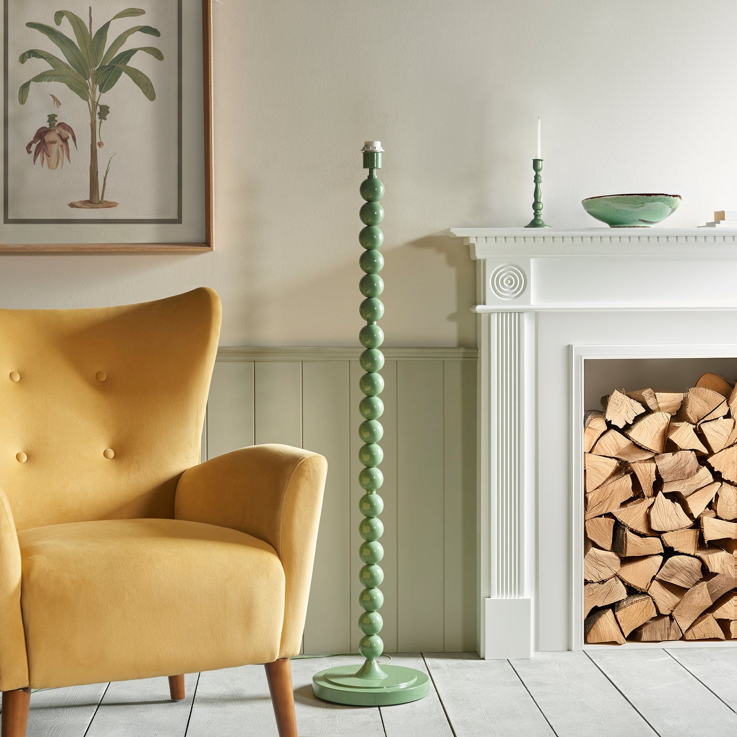 Green lamp base in a room with a yellow armchair, fireplace, and firewood.