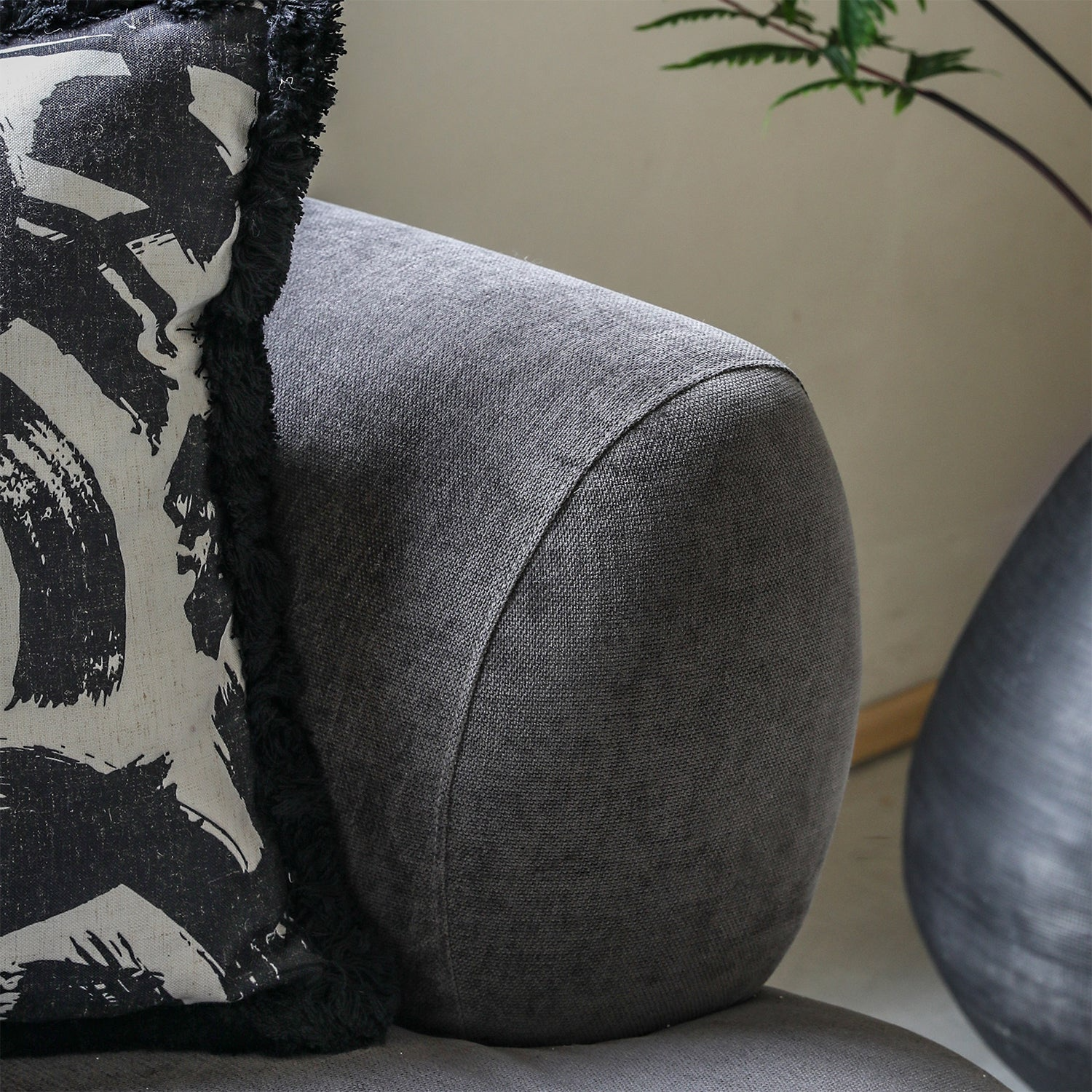 Gray cushion on a sofa with a decorative pillow featuring black and white patterns.