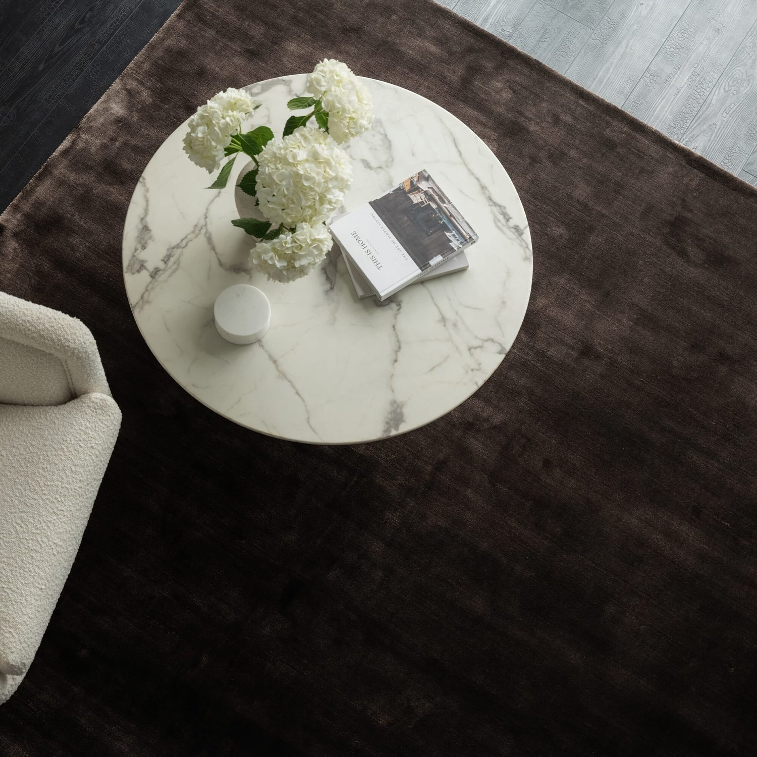 Round marble coffee table with flowers and books on a dark rug