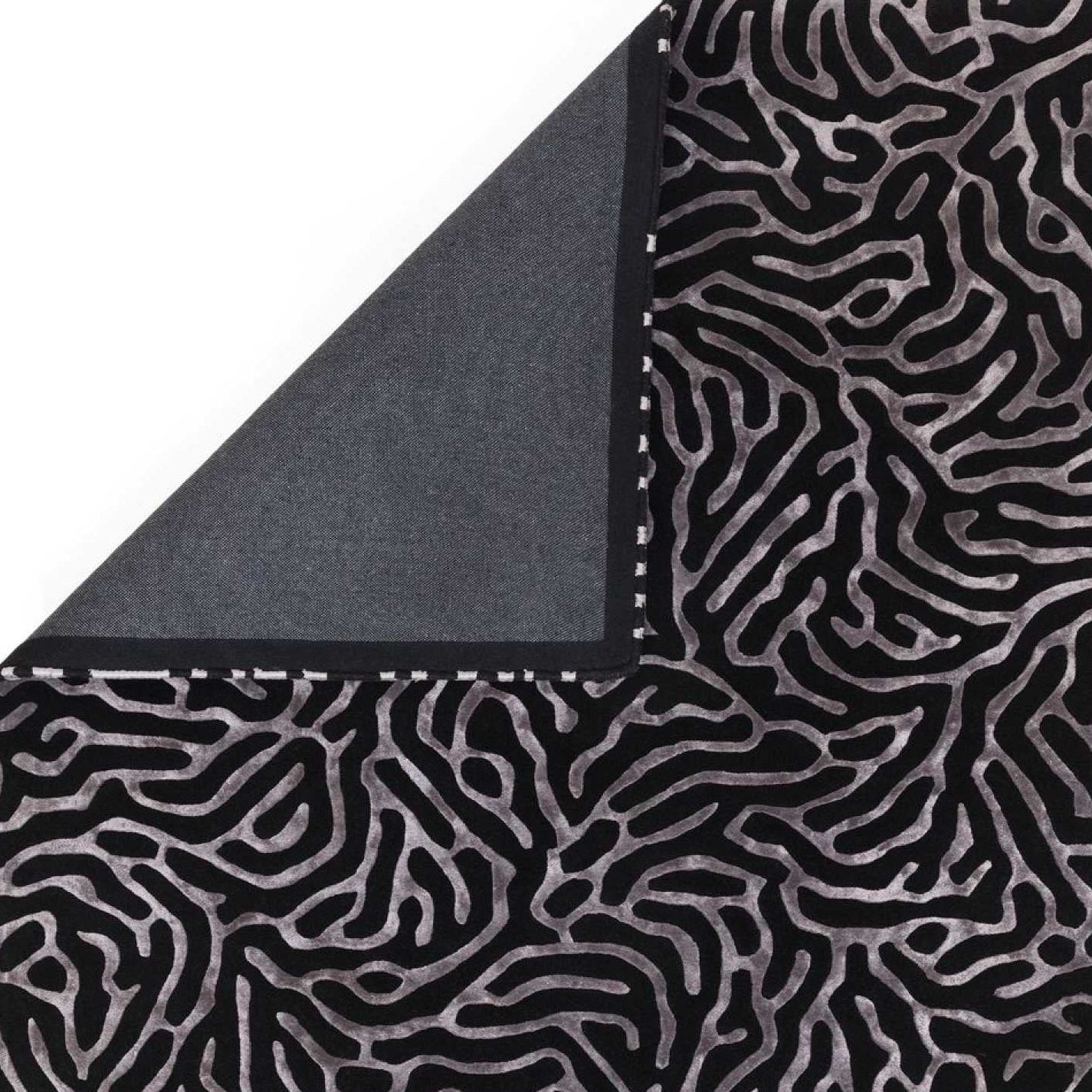 Black and gray patterned rug corner on a white background