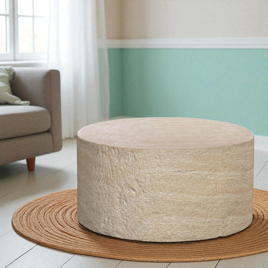 Round coffee table in a living room setting with a couch and green wall.