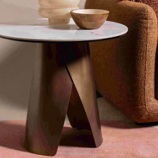 Modern side table with a marble top and brushed bronze legs in a living room setting.