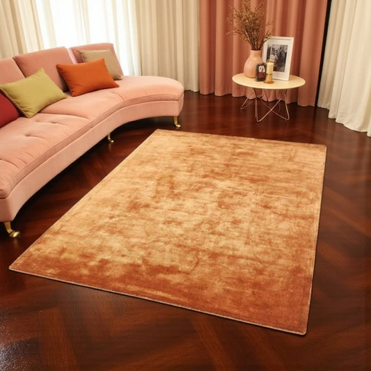copper rug on a wooden floor with a pink sofa and decorative items in the background.