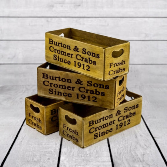 Three wooden crates with 'Burton & Sons Cromer Crabs Since 1912' text on a light wooden background.