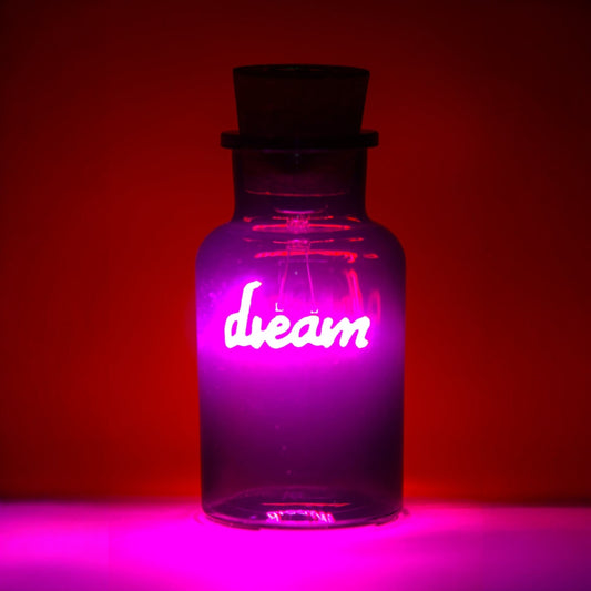 Glass bottle with 'dream' illuminated in pink against a red background