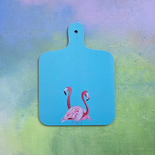 Blue cutting board with pink flamingo design on a colorful background