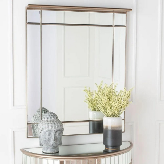 Decorative console table with a mirror, vase, and decorative head in a room.