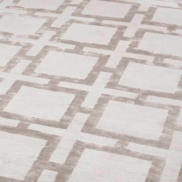 Geometric patterned rug with light beige and cream design on a plain background